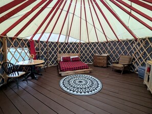 A yurt with a bed, a round table, and two chairs.