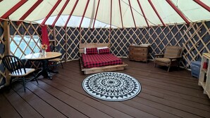 A yurt with a bed, a round table, and two chairs.