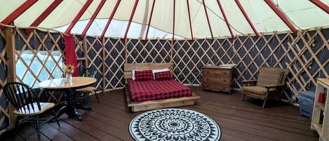 A yurt with a bed, a round table, and two chairs.
