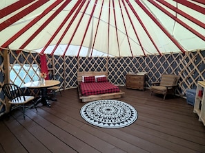 A yurt with a bed, a round table, and two chairs.
