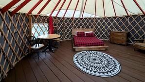 A yurt with a bed, a round table, and a patterned rug.
