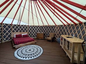 A tent with a bed, a chair, a table, and a patterned rug.