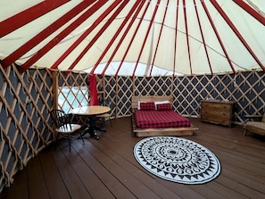 A yurt with a bed, a round table, and a patterned rug.