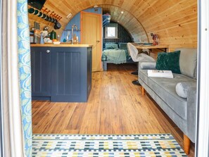 A cozy cabin interior with a wooden ceiling, a kitchen area, a sofa, and a dining table. - Hobhole, in Keal Cotes, 1-bed. (Spilsby)