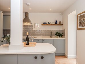 Una cocina moderna con una isla curva, estufa integrada y una lámpara colgante.