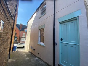 A narrow alleyway with a building on the right, a blue door, and a white car parked in the background. - Picadore Two, Scarborough (Scarborough)