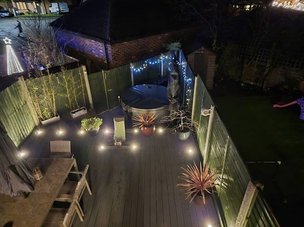 A rooftop deck with a hot tub, string lights, and potted plants.