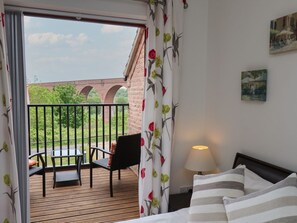 A hotel room with a balcony, a bed, a table, and chairs. - Buffers: Cozy Retreat in Whitby (Whitby)