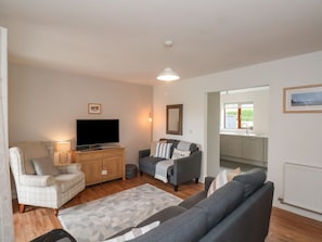 A living room with a sofa, armchair, TV, and a small dining area with a window. - Buffers: Cozy Retreat in Whitby (Whitby)