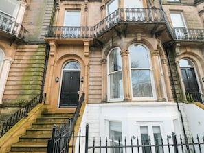 A multi-story building with a black front door, white trim, and a black iron railing on the steps. - Sailors & Mermaids, Scarborough (Scarborough)
