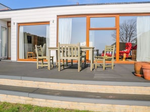 A modern house with a deck, large sliding glass doors, and outdoor furniture. - Harbour View, Mudeford, Christchurch (Christchurch)