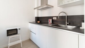 A modern kitchen with a microwave, sink, and stainless steel faucet. - GuestHost - Comfortable 30m2 studio flat, perfect for 2 people, located on the mezzanine floor of a building (steps to access).The accommodation is located in the Calvairate district, a residential area characterized by the green heart of Piazza Insubria (Milan)