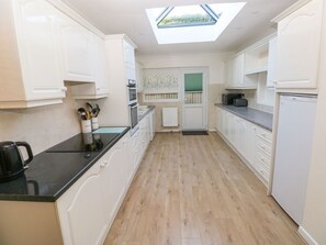 A modern kitchen with white cabinetry, a black countertop, and a skylight. - 30 Long Shepherds Drive, The Mumbles (Swansea)