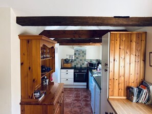 Une cuisine compacte avec un dosseret carrelé, des meubles en bois et un four encastré.