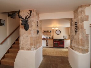 A staircase leading to a kitchen with a rustic stone wall, a clock, and a red oven. - Snape Castle Under Croft and Gardens, Bedale (Bedale)