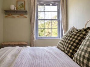Une chambre à coucher avec un lit, une fenêtre, une étagère avec des objets et un banc.