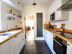 Une cuisine moderne avec des meubles blancs, un plan de travail en bois, un four encastré et un four à micro-ondes.