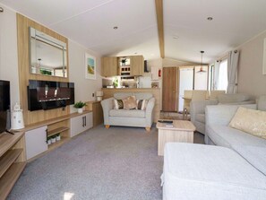 Un espacio habitable compacto con sofá, televisor, zona de cocina y mesa de comedor.