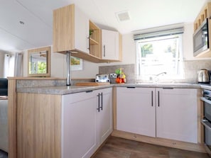 Una cocina moderna con armarios de madera, una encimera, un fregadero, un tostador y una ventana.