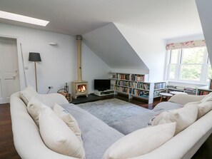 A cozy living room with a sofa, a fireplace, a bookshelf, and a television.