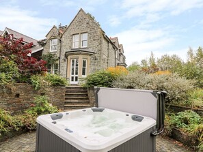 A stone house with a hot tub in the garden.