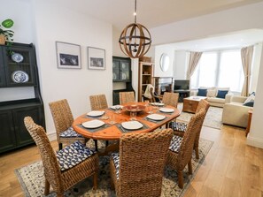 A dining area with a round table, wicker chairs, and a central light fixture. - Seafarers, Scarborough (Scarborough)