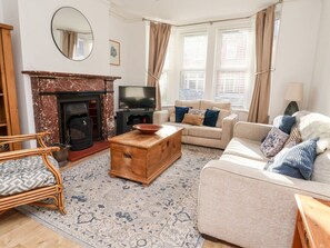 A living room with a fireplace, a television, a sofa, a wooden coffee table, and a patterned rug. - Seafarers, Scarborough (Scarborough)