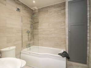 Een moderne badkamer met een bad, douche en toilet.