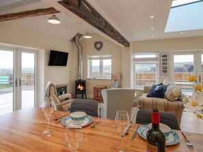 A dining area with a table set for four, a fireplace, and a view of the countryside.