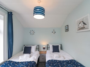 Ein Doppelzimmer mit zwei Betten, einem Nachttisch, einer Lampe, einer Uhr und einem Bild an der Wand.
