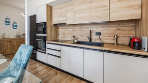 Une cuisine moderne avec des armoires blanches, un plan de travail en bois, un four encastré et une machine à café.