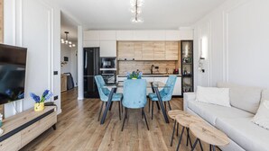 Un salon moderne comprenant un canapé, un téléviseur et un coin repas avec des chaises et une table.