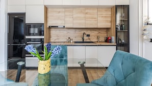 Une cuisine moderne avec des meubles en bois, une table à manger en verre et un canapé bleu.