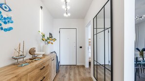 Un couloir avec une commode en bois, un petit modèle de bateau et un vase rempli de fleurs.