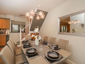 A dining area with a long table set for six, surrounded by chairs, with a chandelier above. - Tudor House, Symonds Yat (Ross-on-Wye)