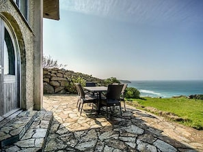 Un patio de piedra con una mesa y sillas con vista al océano.