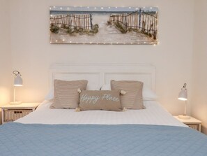 Ein ordentlich eingerichtetes Schlafzimmer mit einem Bett, zwei Nachttischen, einem Kopfteil und einem an der Wand hängenden Bild.
