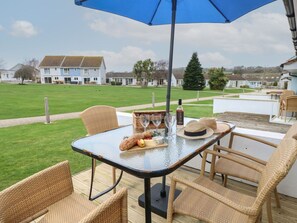 A patio with wicker furniture, a table set with food and drinks, and a view of houses in the background.