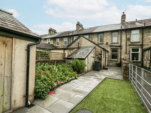 A residential courtyard with stone paving, a grassy lawn, and a metal fence. - Robin's Retreat, Kendal (Kendal)