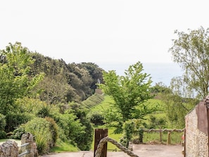 A rustic gate leading to a lush, green landscape with a hill in the background. - The Lobster Pot, Ventnor (Ventnor)
