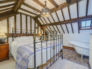Ein Schlafzimmer mit einem Himmelbett, Holzboden, einer Kandelaberleuchte, einem weißen Heizkörper und einer weißen Badewanne.