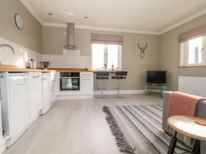 A modern kitchen with white appliances, a dining area with a TV, and a cozy seating area. - Roughwood, Poulner, Hampshire (Ringwood)