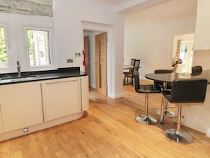 A modern kitchen with a central island, a dining area with a table and chairs, and a visible door leading to another room.