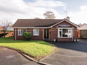 A two-story brick house with a tiled roof, a front door, and a small front yard. - CONEYVILLE, open-plan, Culmore Point (Londonderry)
