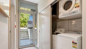 Uma lavanderia compacta com máquina de lavar, secadora e porta de vidro que dá para o exterior.