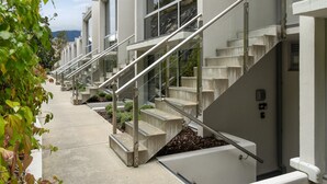 Uma fileira de edifícios modernos com escadas externas, degraus de concreto e guarda-corpos de metal.