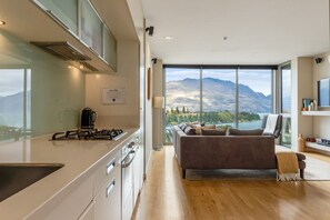 Une cuisine moderne équipée d’une cuisinière à gaz, d’une machine à café et offrant une vue sur les montagnes grâce à de grandes fenêtres.