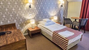 A hotel room with a bed, two bedside tables with lamps, a small table with chairs, and a patterned wall. - Hotel Lord Krosno (Krosno)
