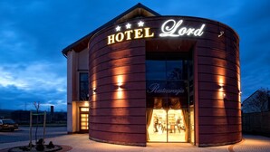 A hotel with a curved facade, illuminated signage, and a visible restaurant entrance. - Hotel Lord Krosno (Krosno)