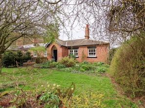 A brick house with a garden, a chimney, and a small table.